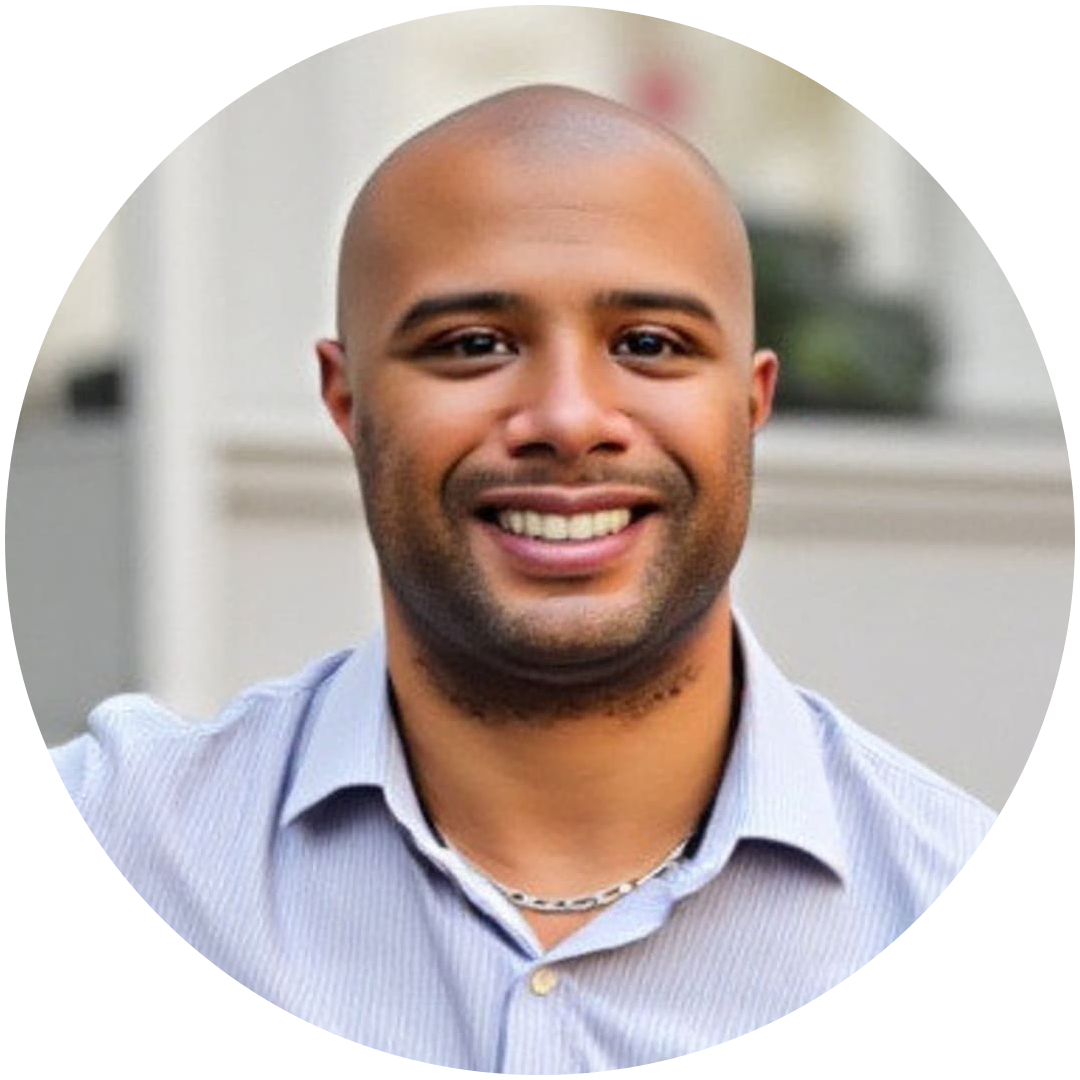 A man with a shaved head and trimmed beard, wearing a light-colored collared shirt and chain necklace, smiles at the camera. The neutral background highlights his approachable look—perfect for discussing mortgage solutions.